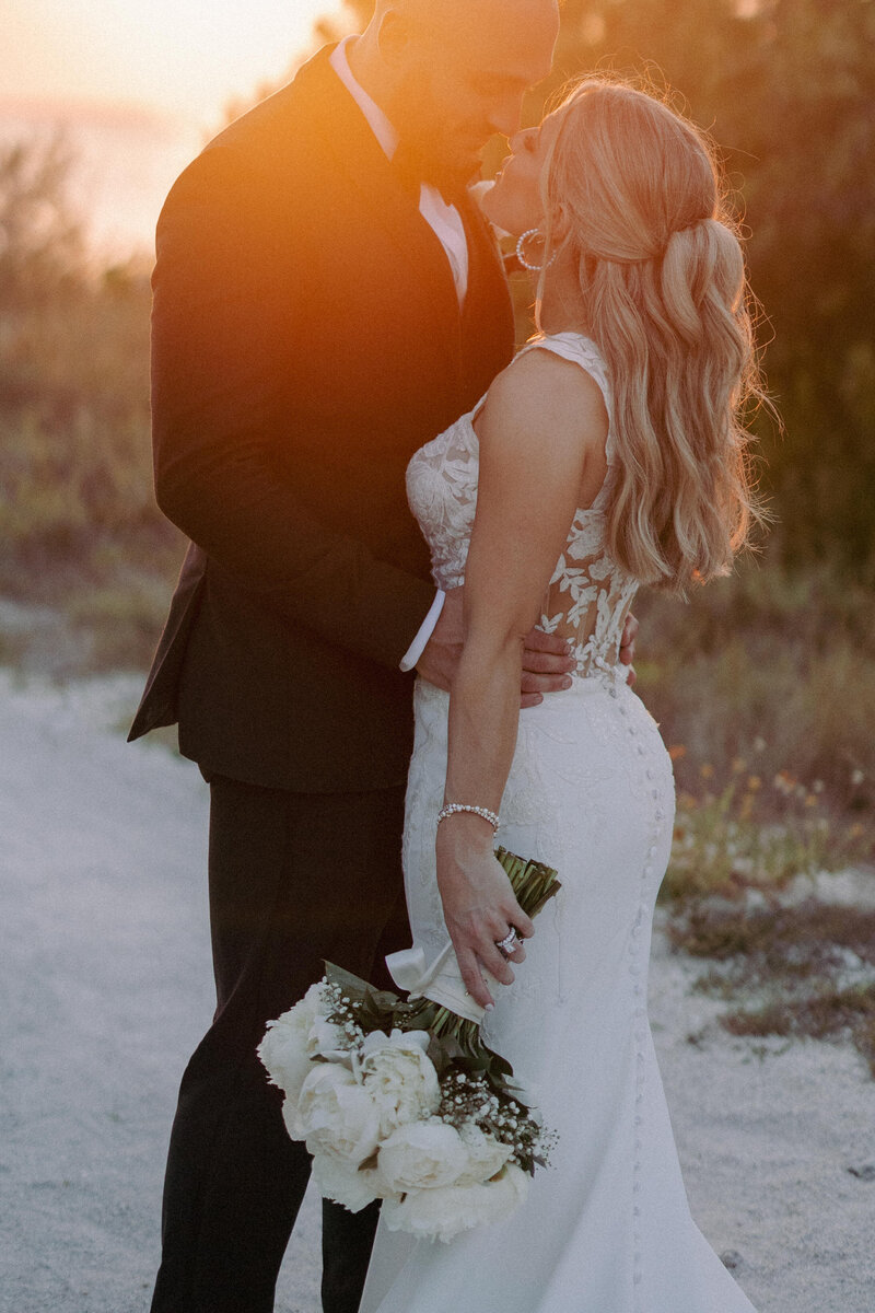 bride and groom embracing while standing on the beach