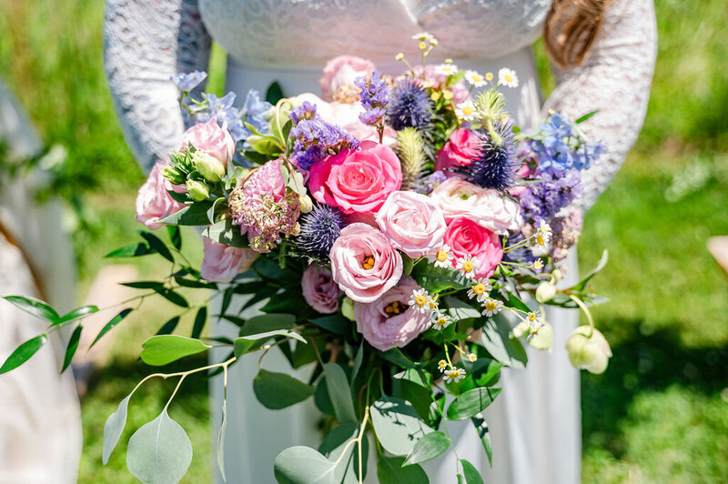 Close-up of a colorful wedding bouquet with pink and purple flowers.