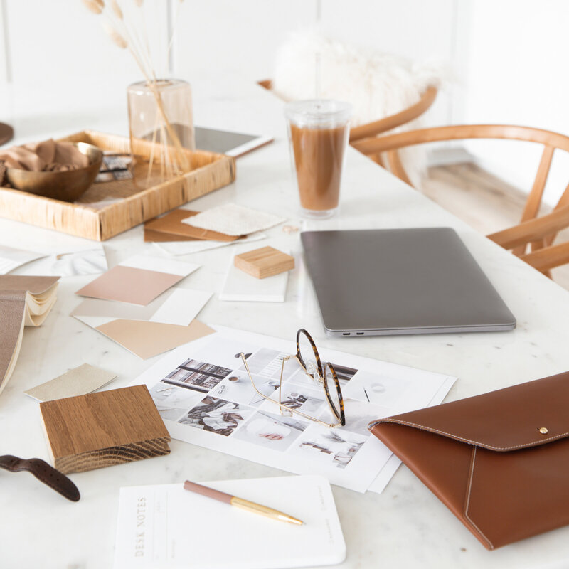 A beautifully styled workspace featuring a laptop, coffee, glasses, and design materials on a marble table, representing the organised and professional approach of KP Virtual Assistance’s Studio Ninja audits for photographers