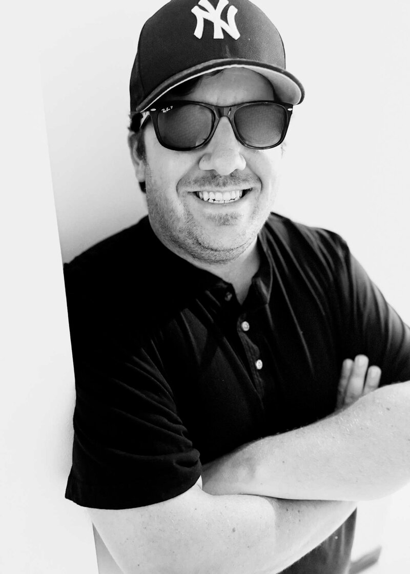 Google Ads agency specialist wearing black sunglasses, a black t-shirt, and a hat, demonstrating a professional and confident look.