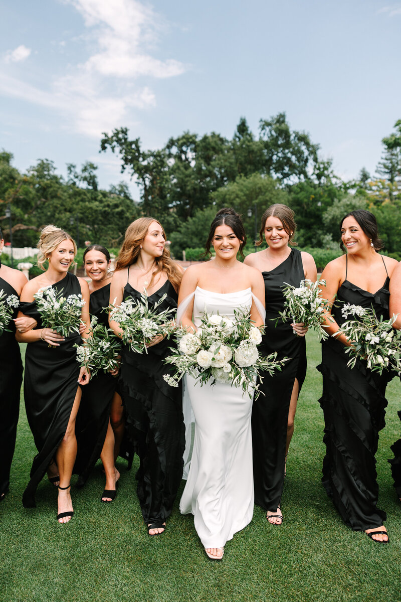 bride and bridesmaids at silverado resort walking with white and green bouquets and black bridesmaid dresses