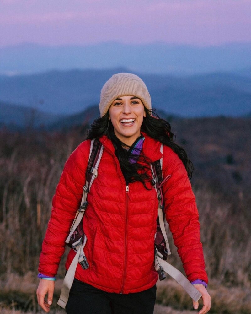 female content creator madelyneonthemove in a red jacket on a mountain