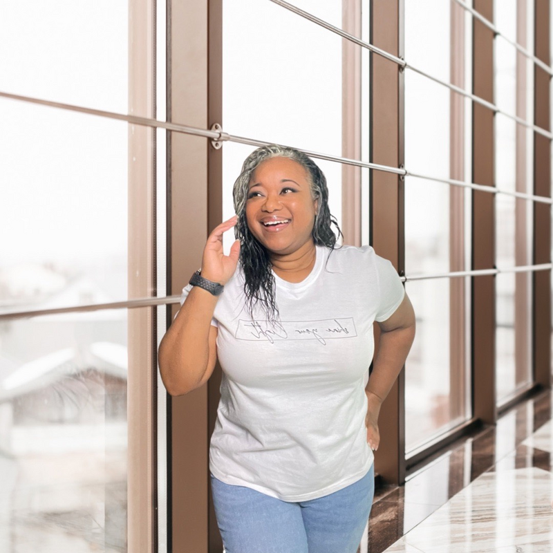 Letitia Hopkins smiling while walking through an office hallway, glancing up with confidence and ease, embodying self-love, alignment, and Main Character Energy as a life, love, and relationship coach guiding women to create empowered lives and relationships.