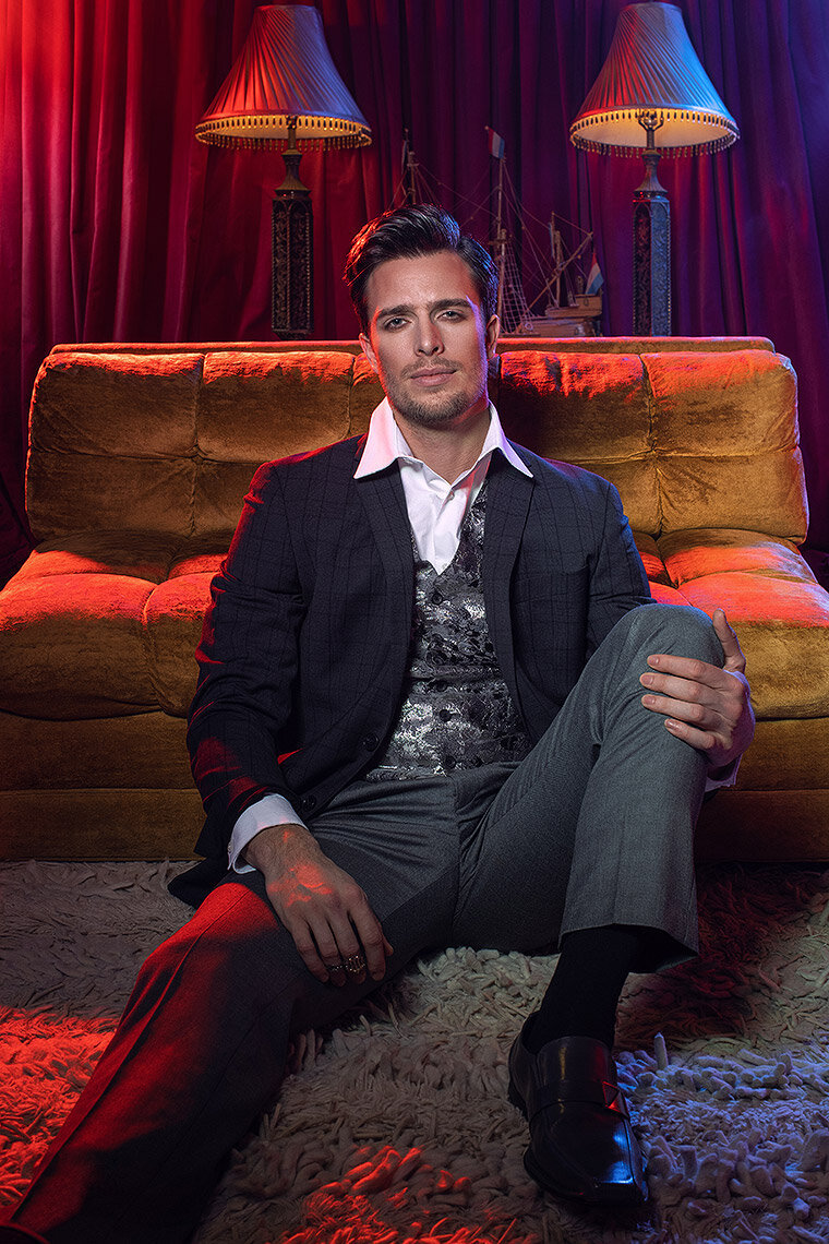 Stylish portrait of Nick Zibro seated in a modern lounge with vibrant lighting, exuding confidence, shot by Ylva Erevall.