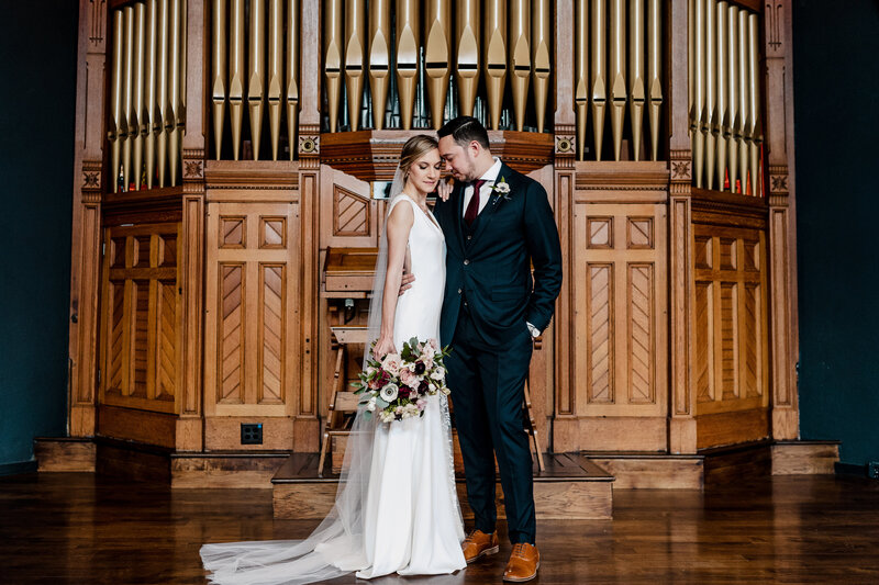 bride and groom posing in front of organ pipes