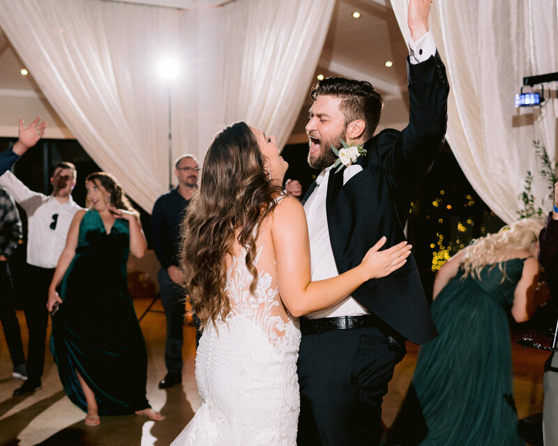 bride and groom dancing and laughing, singing along to songs at reception by austin wedding photographer