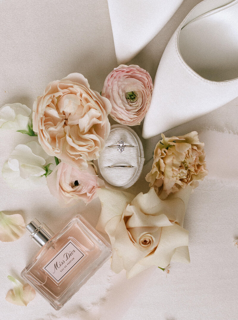 wedding day details of perfume, bridal shoes, flowers, and wedding rings