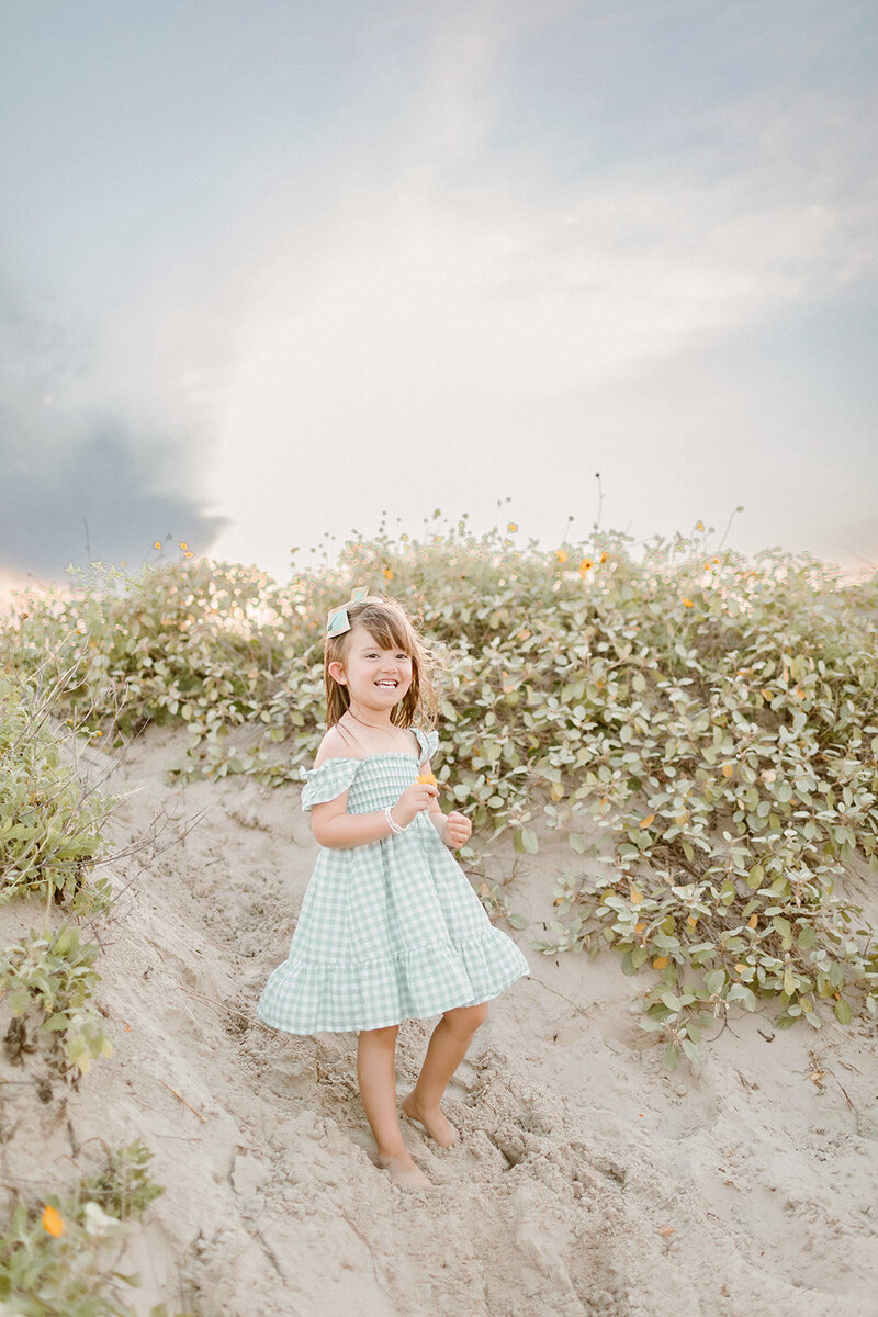 Little girl wearing a dress and smiling on the beach