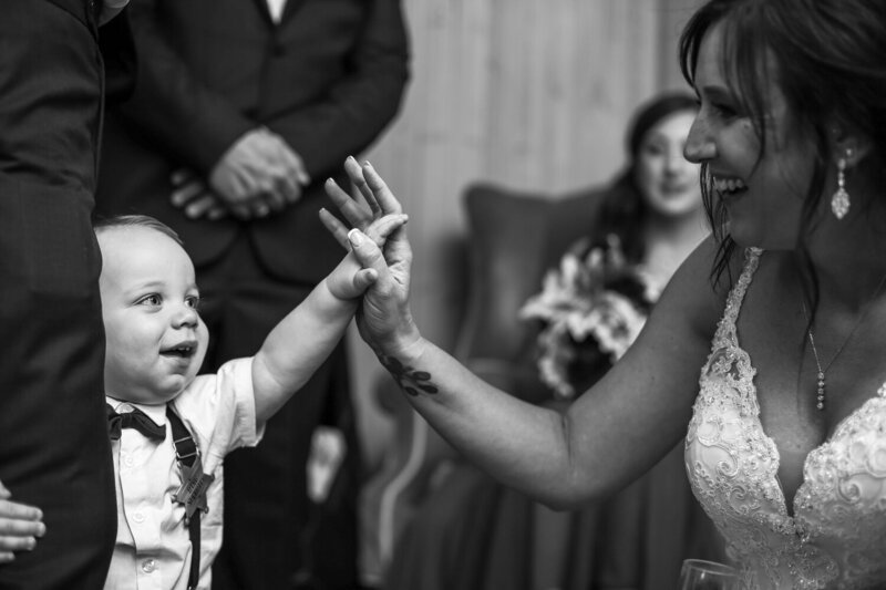 Young ringbearer high fives bride before wedding at Whispering Trees