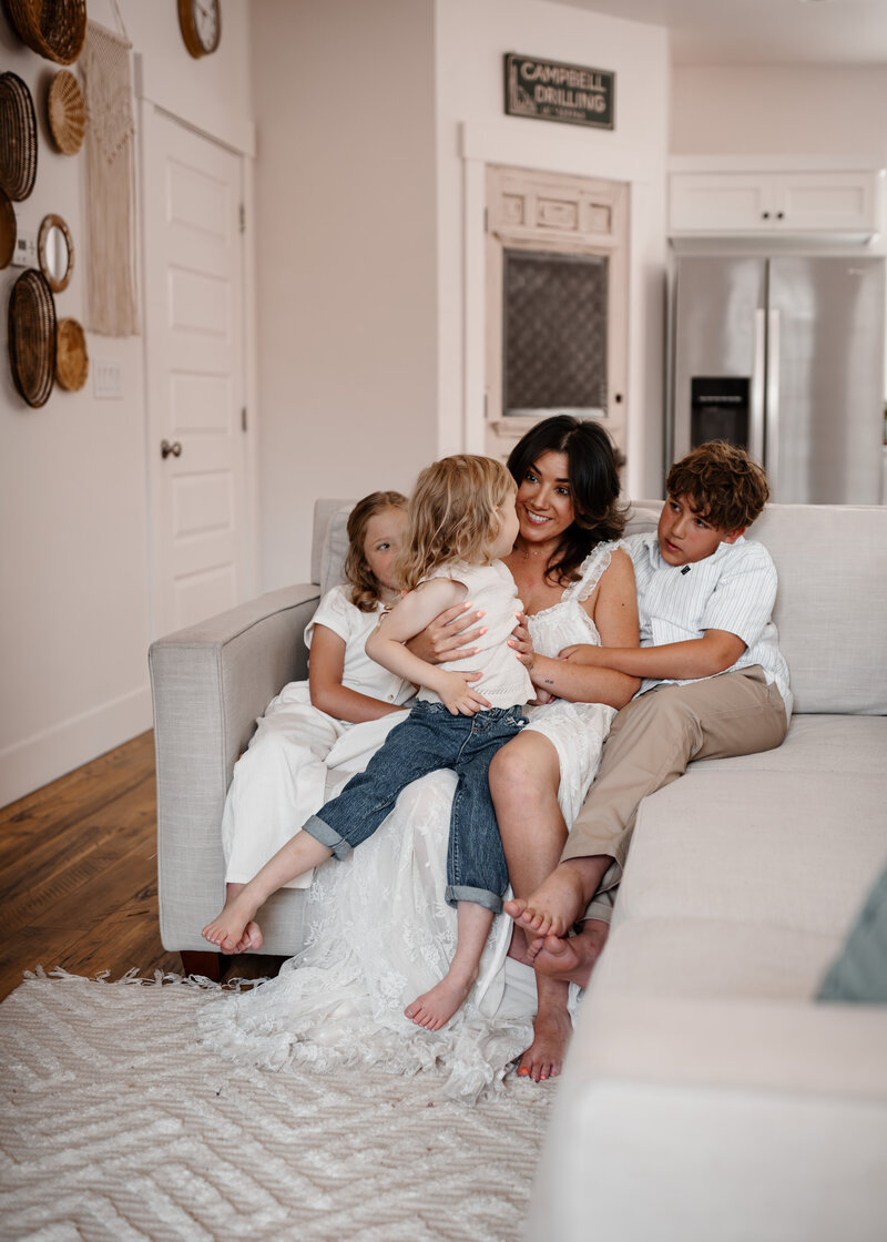 A mother snuggling her three children on a white sofa in a gorgeous white farm house in Boise Idaho. 