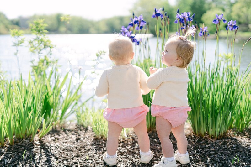 twin baby girls looking out at the lake by Japanese lilies