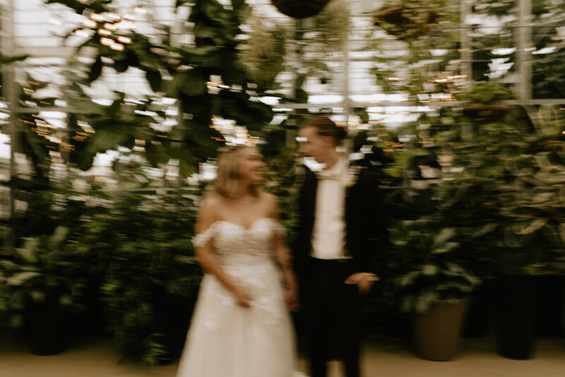 A wedding couple holding hands in a greenhouse
