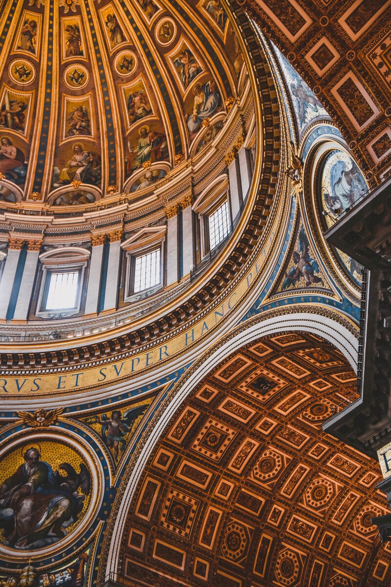 Detailed interior of a historic cathedral dome with ornate gold and fresco artwork, representing sacred and cultural heritage travel.


