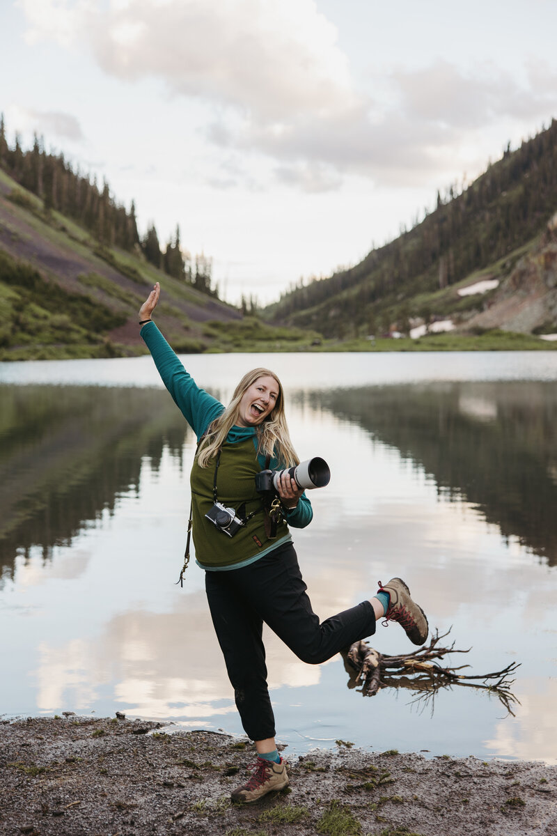 Female photographer excitedly standing by an alpine like in the mountains