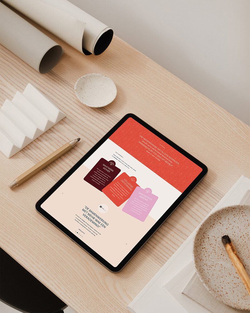 Tablet op houten tafel toont de MEHR-website met kernwaarden en klantbeoordeling