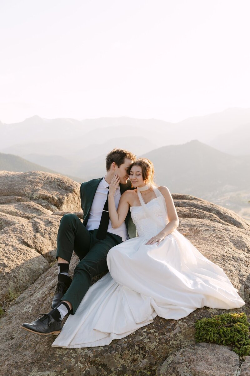 Couple sitting on rocky overlook during their Colorado elopement in the mountains — Estes Park elopement photography.