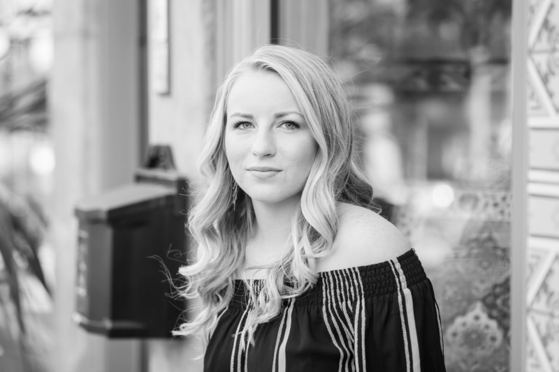 black and white photo of  high school senior girl sitting on ledge of art find tile shop in downtown wooster ohio photographed by Jamie Lynette Photography canton senior photographer
