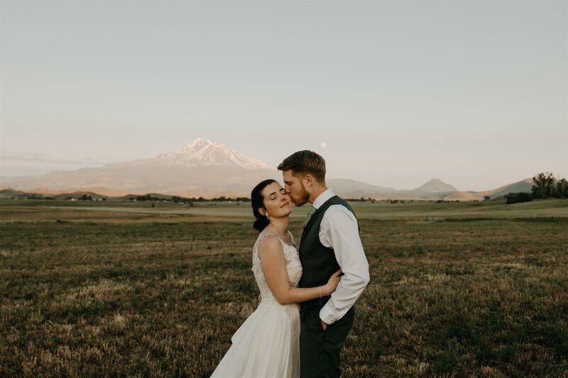 Microwedding couple posing in front of Mount Shasta with full moon during blue hour