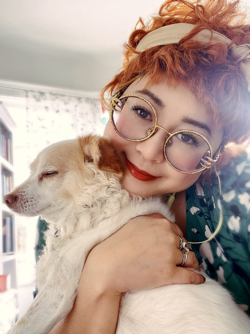 redhead Asian American woman holding a little white dog