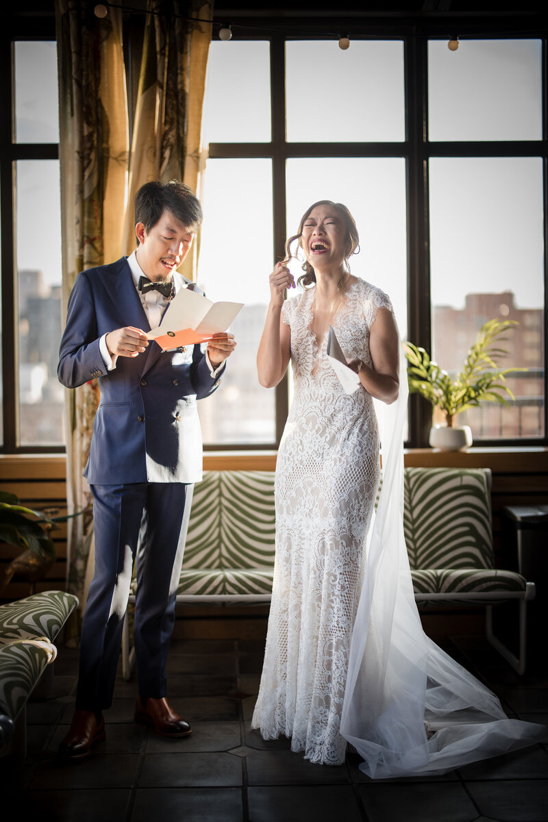 A bride and groom laughing together as they read each other letters.