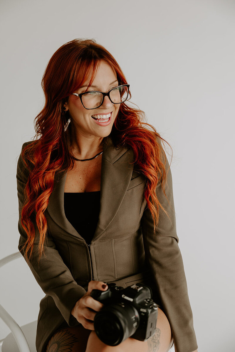 woman with red hair smiling in a olive blazer