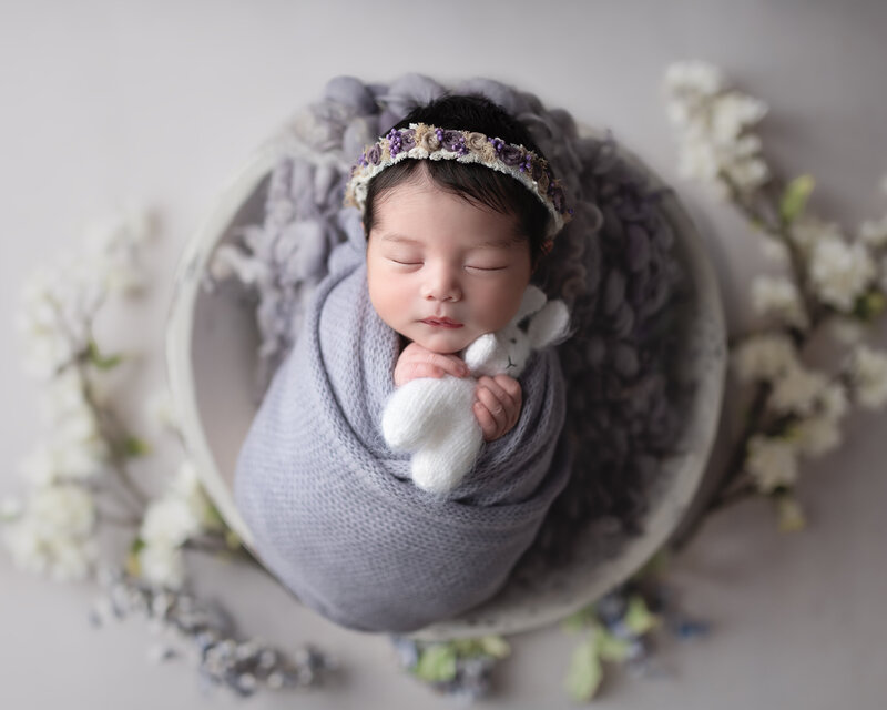 Surrounded by florals and dressed in lavender, this baby girl’s portrait is as soft and sweet as springtime dreams.