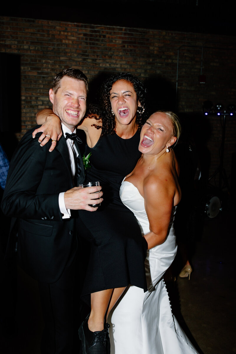 Bride and groom lift their wedding photographer, Teresa Williams, in the air at their wedding reception