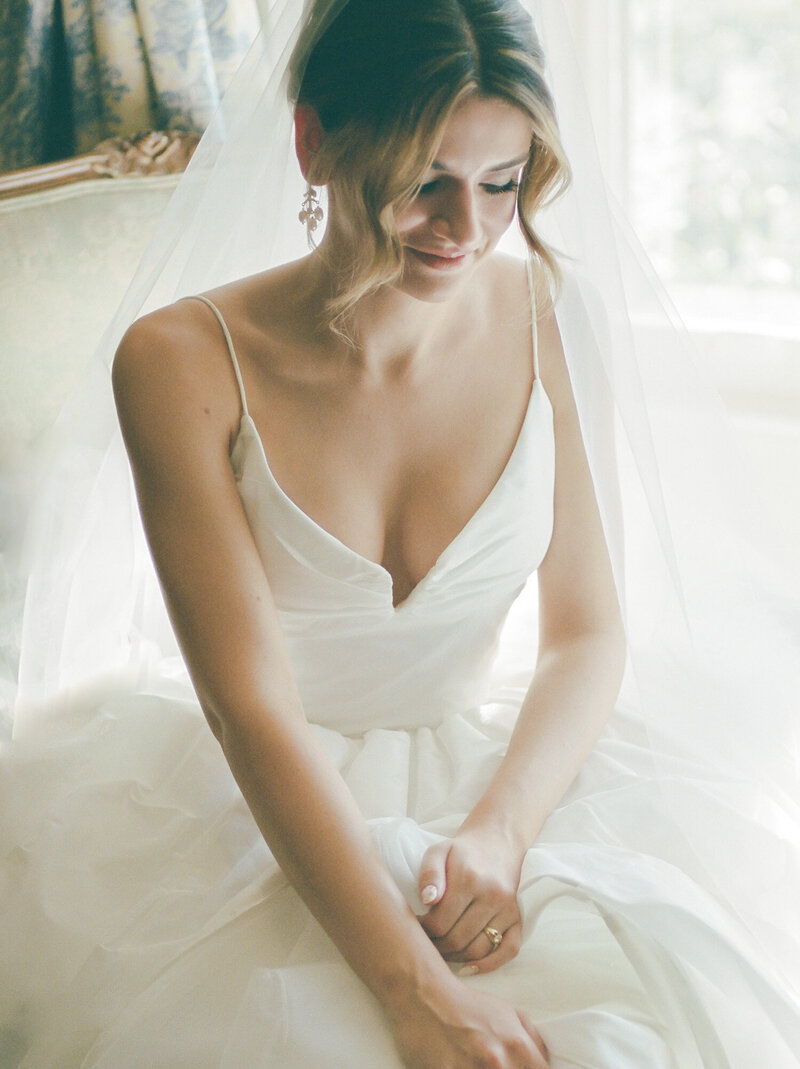 painterly film bridal portrait, bride in stylish ballgown, antique pearl earrings, cathedral veil smiles peacefully