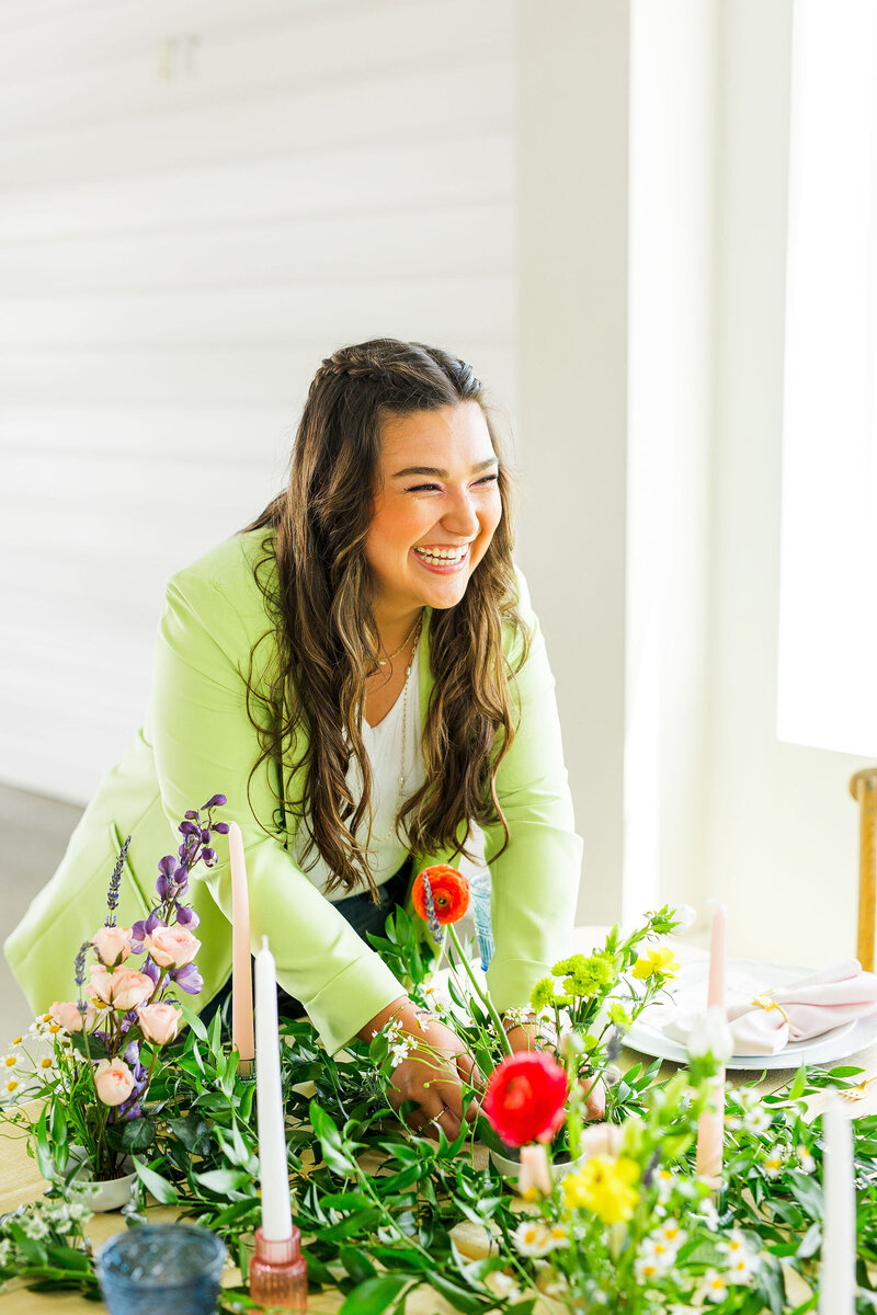 Makayla Rivera arranging a colorful tablescape and wearing a bright green blazer