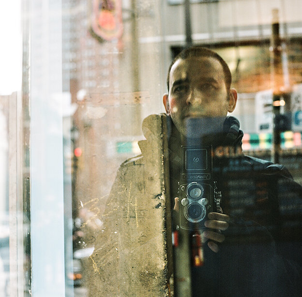 A film portrait of russ hickman photography in the reflection of a window in philadelphia, pa.