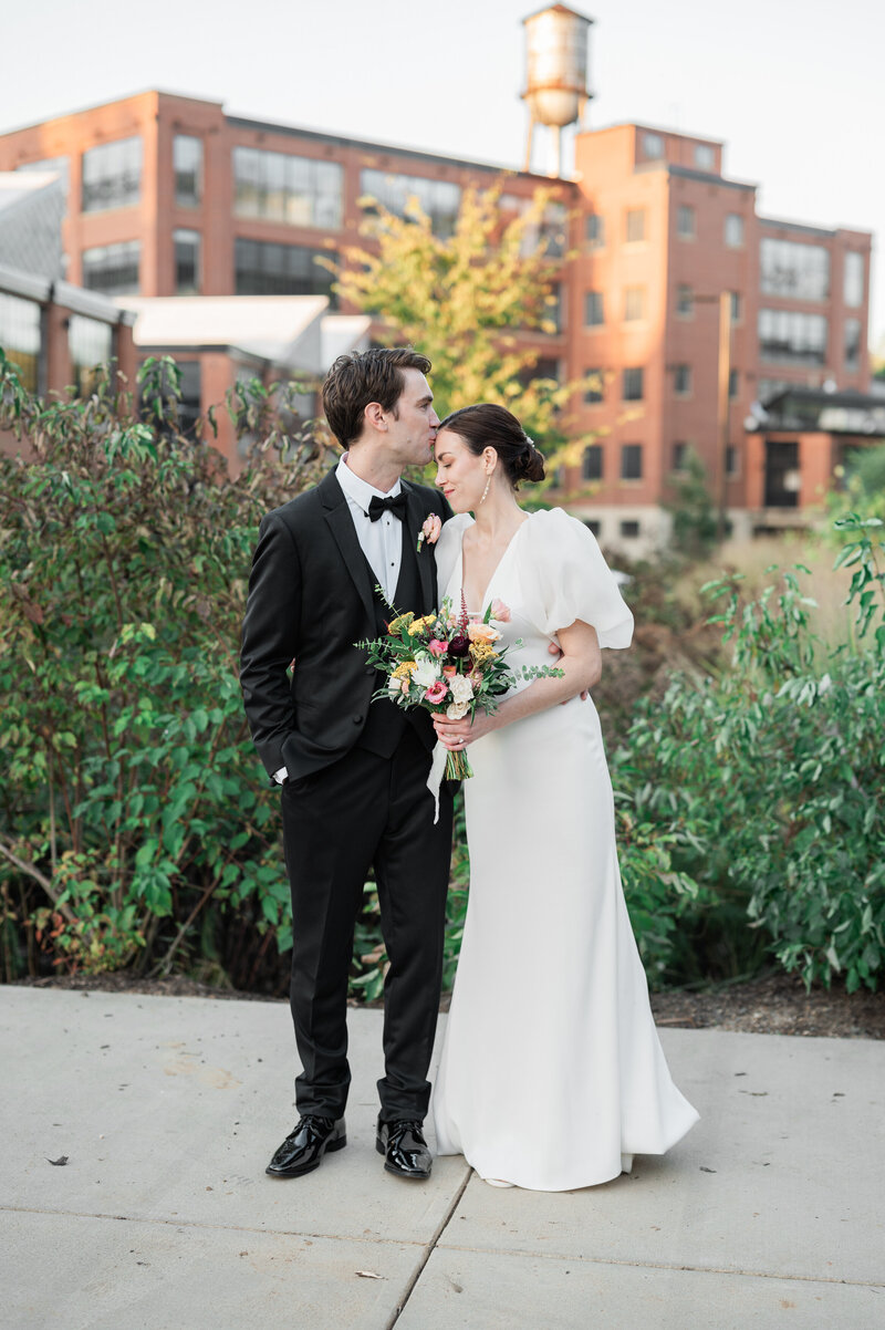 A person kissing their partner's head on their wedding day