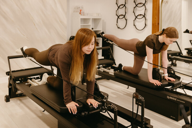 A man is in a pilates pose with his legs wide apart and arms stretched out.
