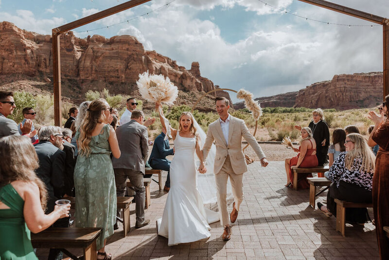 bride and groom in front of the red earth venue sign