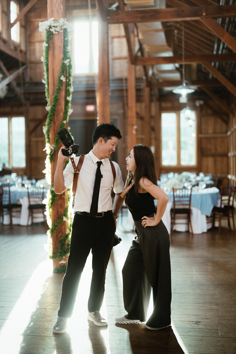 The couple looking at each other and laughing with cameras on their hand on the wedding day by los angeles wedding videographer, Jimmy Shin Films
