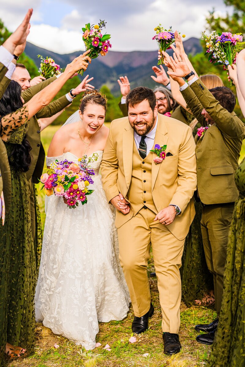 bride and groom under bridal wedding party hands laughing smiling mountain background in Flagstaff