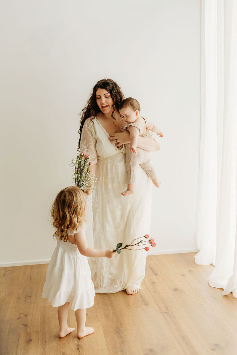 Mt Hood Elopement Photographer Lindsey Wickert dances with her two daughters n a beige dress in a  photography studio