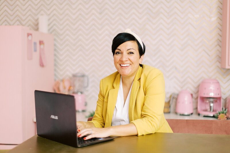 woman wearing a pink headband and yellow blazer typing on computer at the nashville pinky house