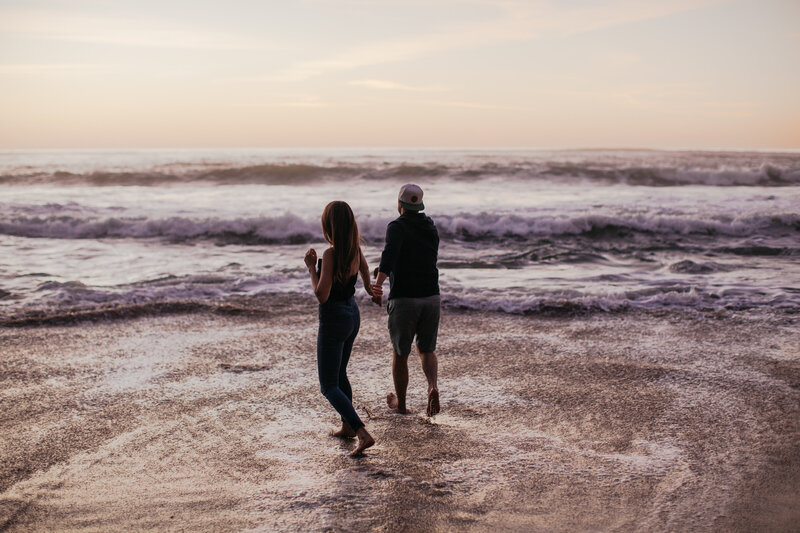 Couple walking into the ocean during sunset San Diego engagement session