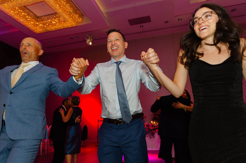 wedding guests holding hands and dancing during a Chateau le Parc wedding reception.  Captured by Ottawa wedding photographer JEMMAN Photography