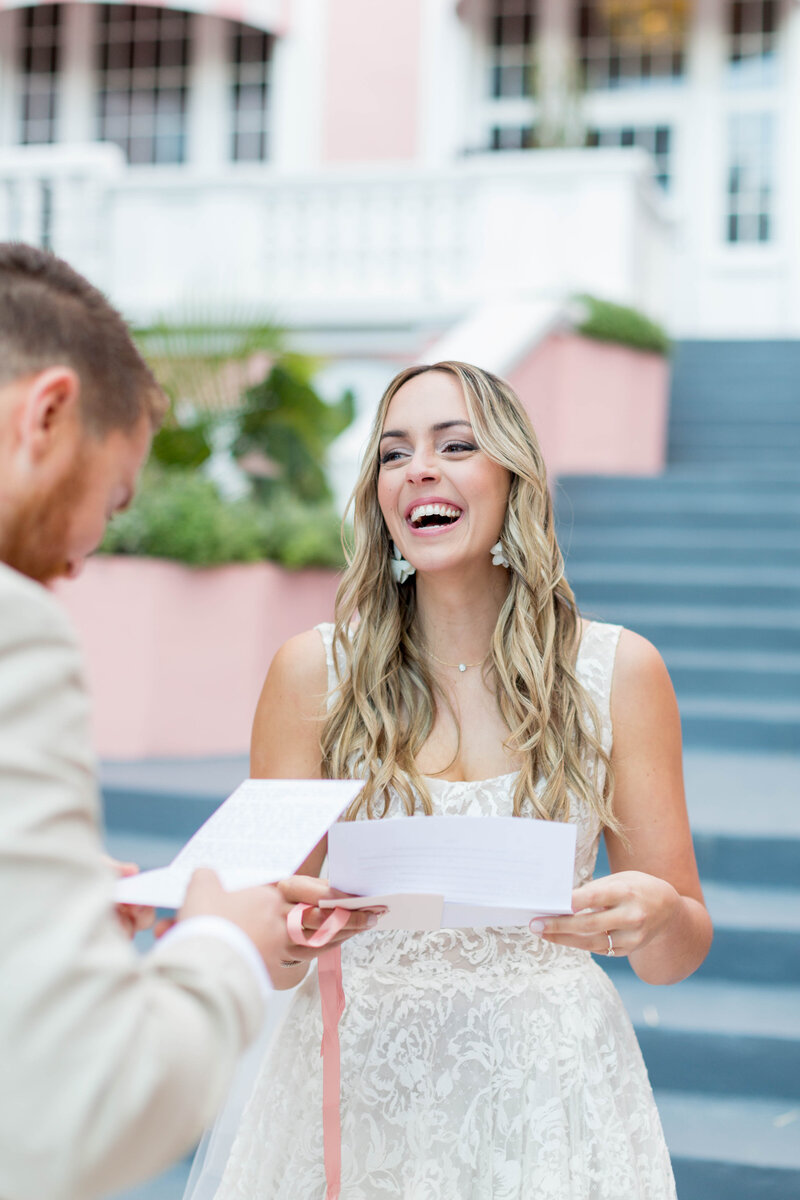 Bride laughing with groom as he says his vows at luxury outdoor wedding The Don Ceaser