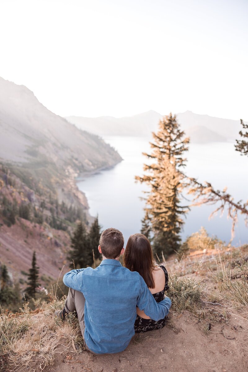Engaged couple sitting and looking at Crater Lake