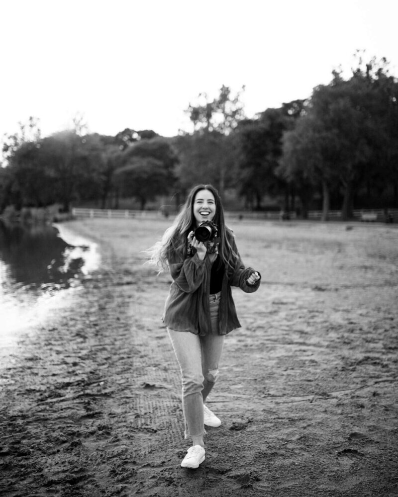 Photographer holding her camera, walking on a beach in a black and white photo