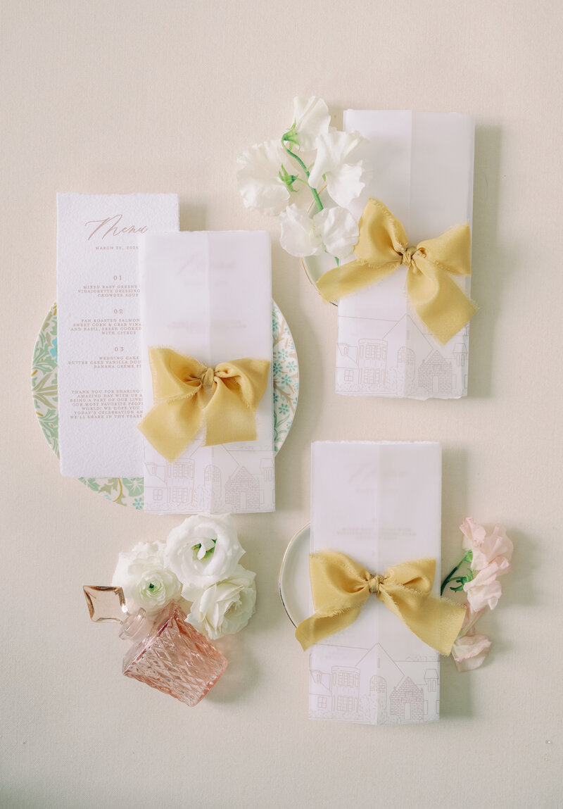 A flat lay of wedding reception menus in cream, white and pink at a high end wedding in Michigan