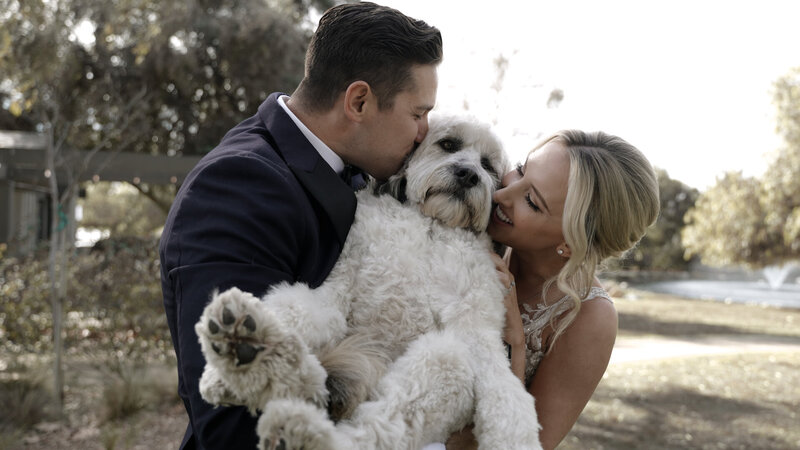 Bride and groom having their portrait session with holding their big dog, cuddling and kissing to their lovely dog.  Filmed by Tales of Woo, wedding videographer in los angeles