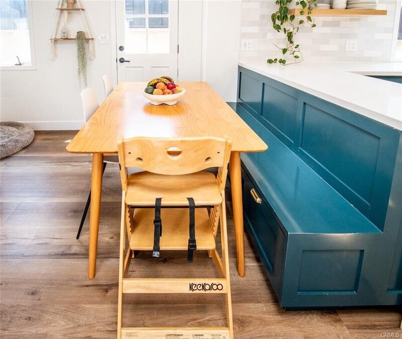 Eclectic Spanish Revival kitchen and dining area with bold blue cabinetry, natural wood tones, and high chair seating for family-friendly design.