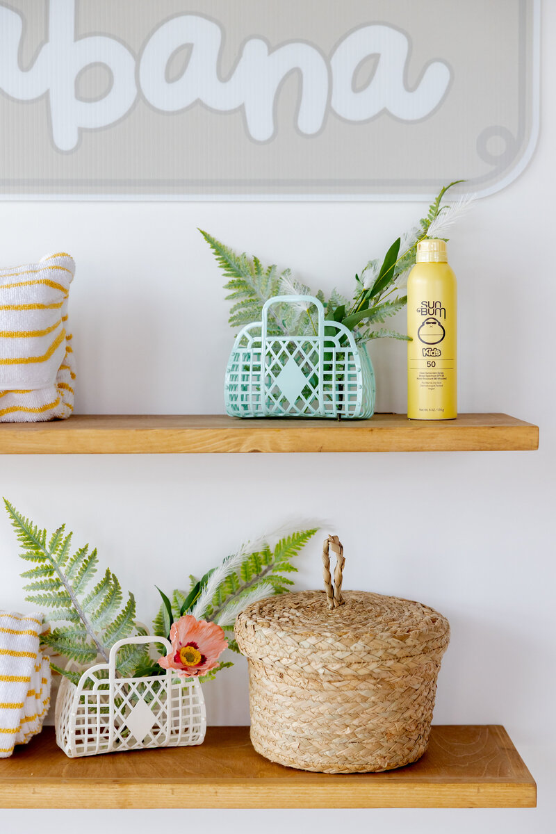 Beach shelves decorated with pool items, baskets, and sunscreen.