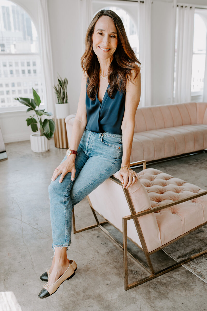 Ashley sits smiling on a couch