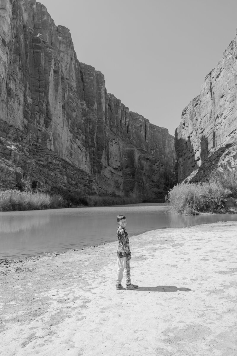 Black and white image of a boy exploring Santa Elena Canyon, styled with editorial composition by Texas-based luxury photographer Erin Marcin.