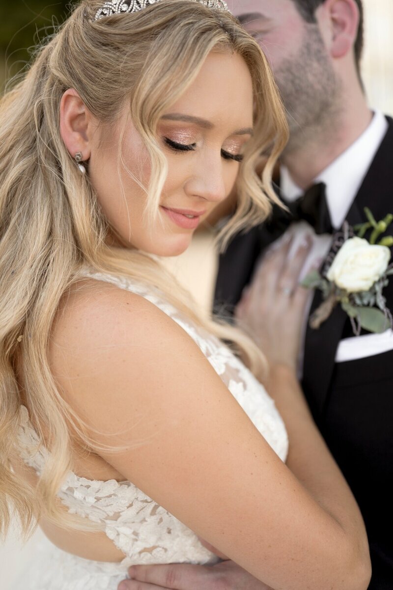Bride and groom kissing underneath luxurious floral arch with white roses and greenery