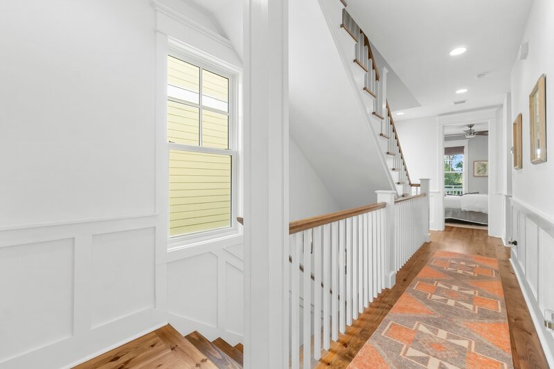 Light-filled second floor hallway with stairs leading to bedrooms at Tangerine Dream in Carillon Beach near Alys Beach.
